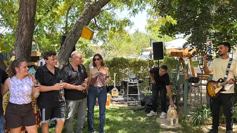 הופעה חיה בחצר היקב — גיטריסט מנגן בין העצים ואורחים מאזינים עם כוסות יין ביד