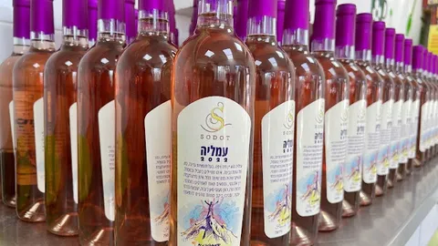 שורת בקבוקי רוזה עמליה 2022 של יקב סודות עם פקקים סגולים, רגע אחרי הדבקת התוויות